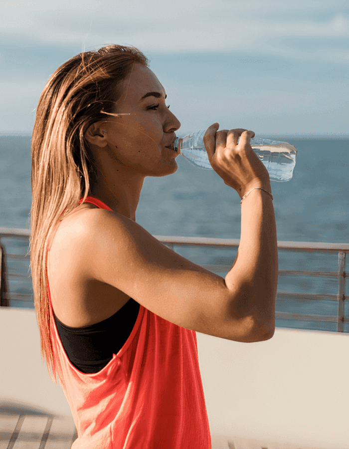 Woman in athletic gear drinking bottled water outside
