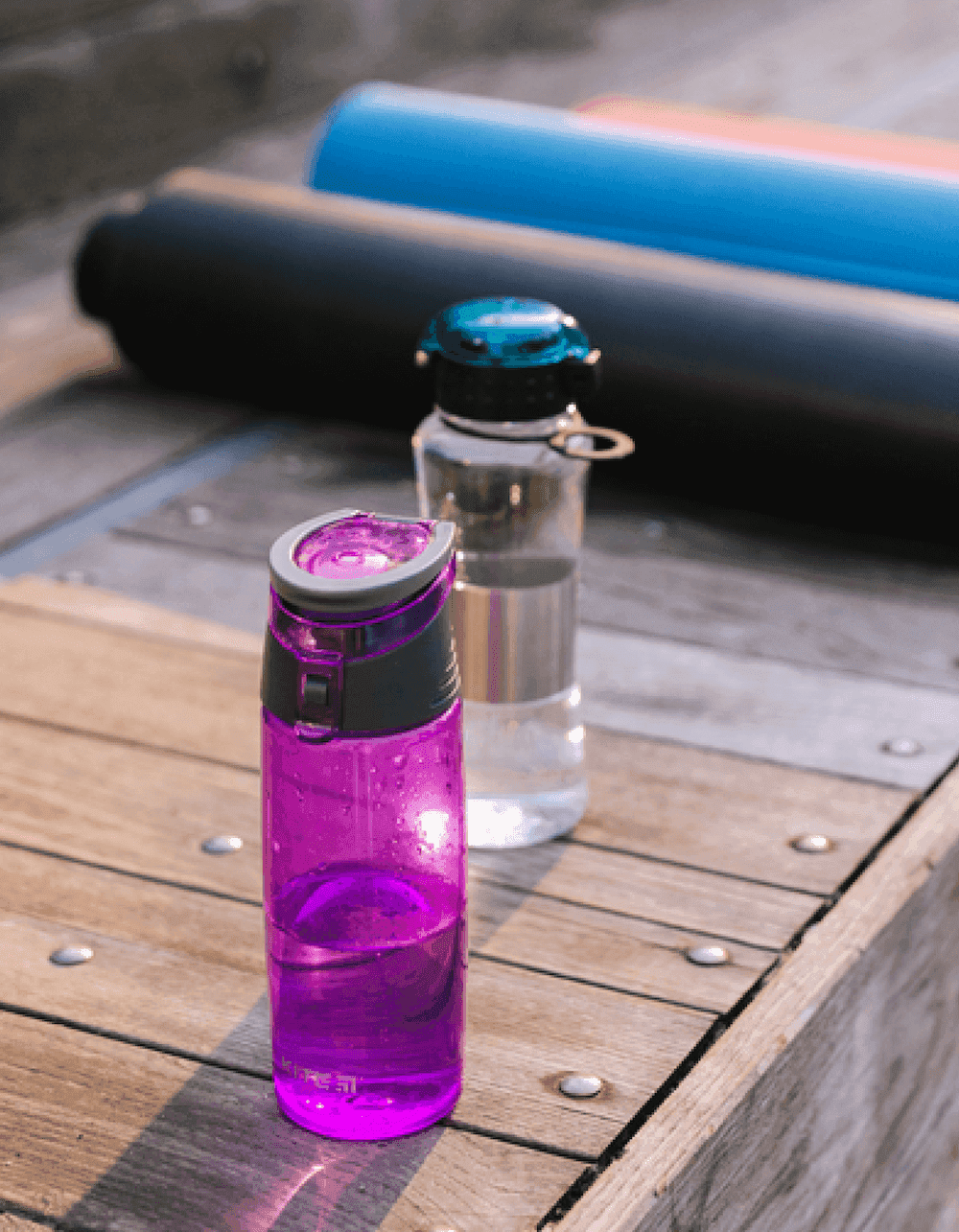 Purple and clear water bottles on wood deck
